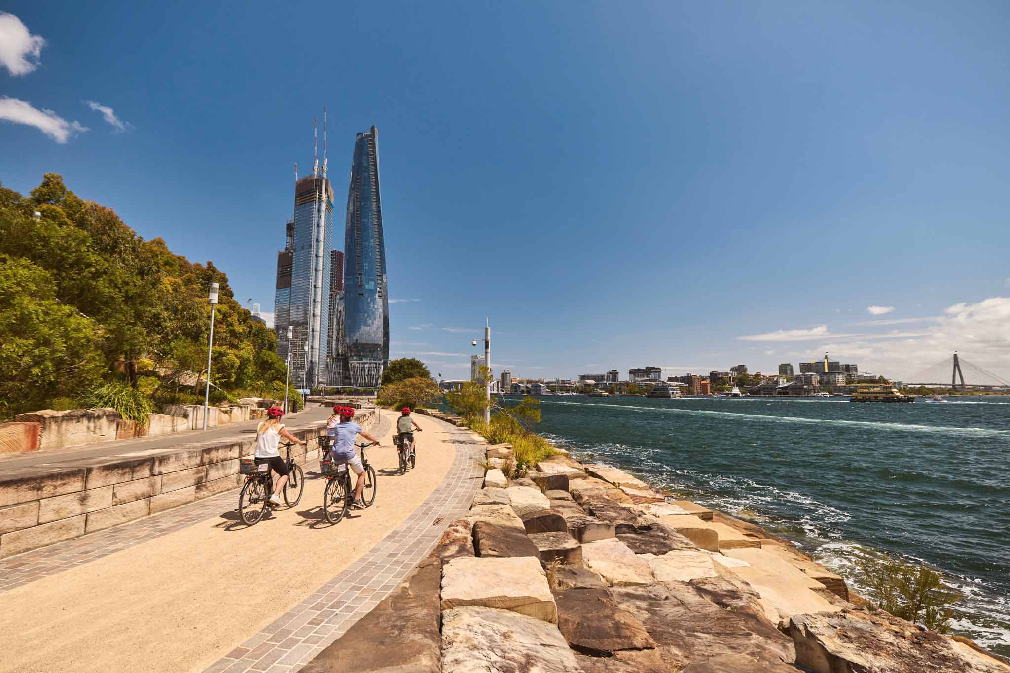 Three cyclists ride along a waterfront path