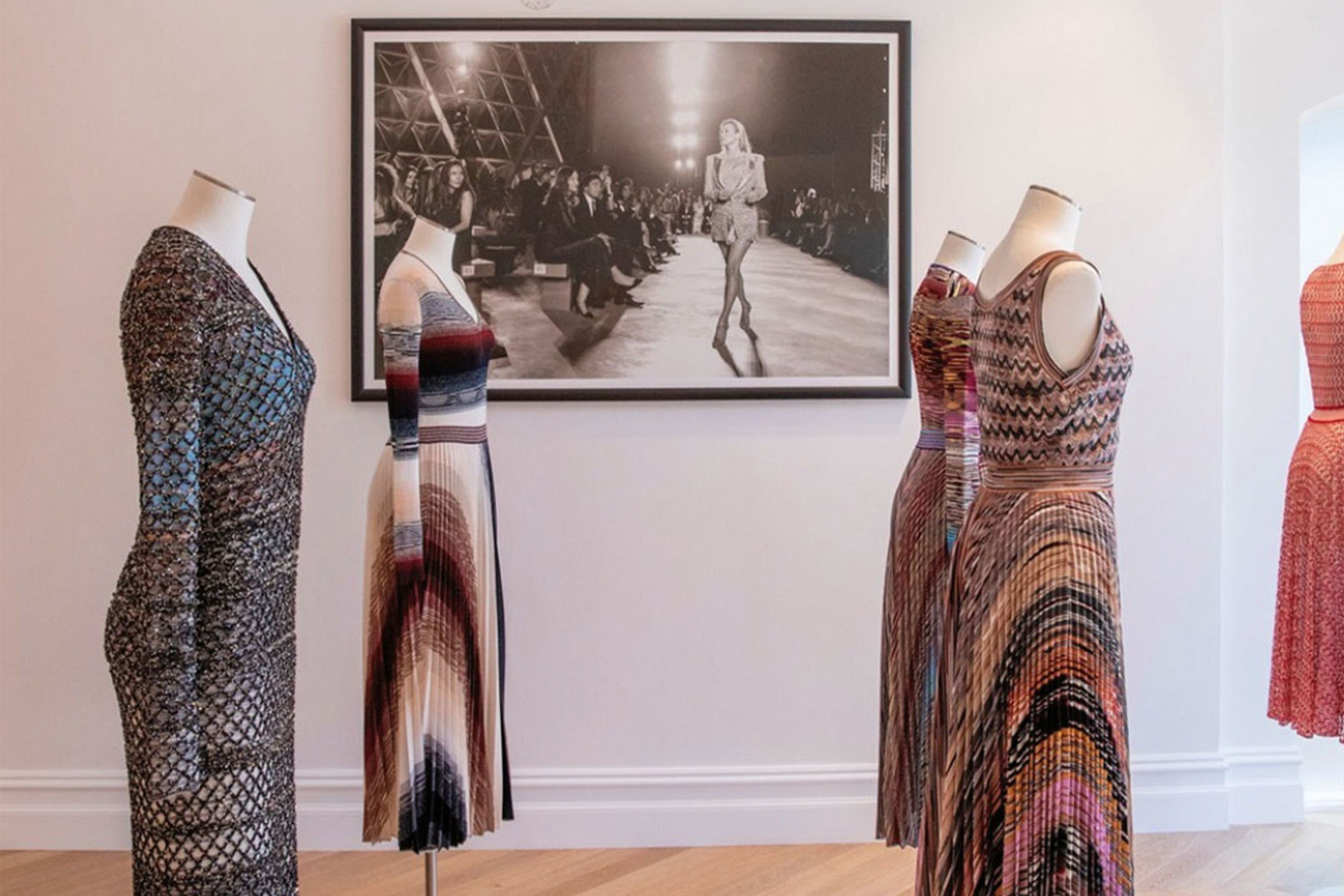 Knit dresses displayed on mannequins in a gallery setting, showcasing various patterns and textures