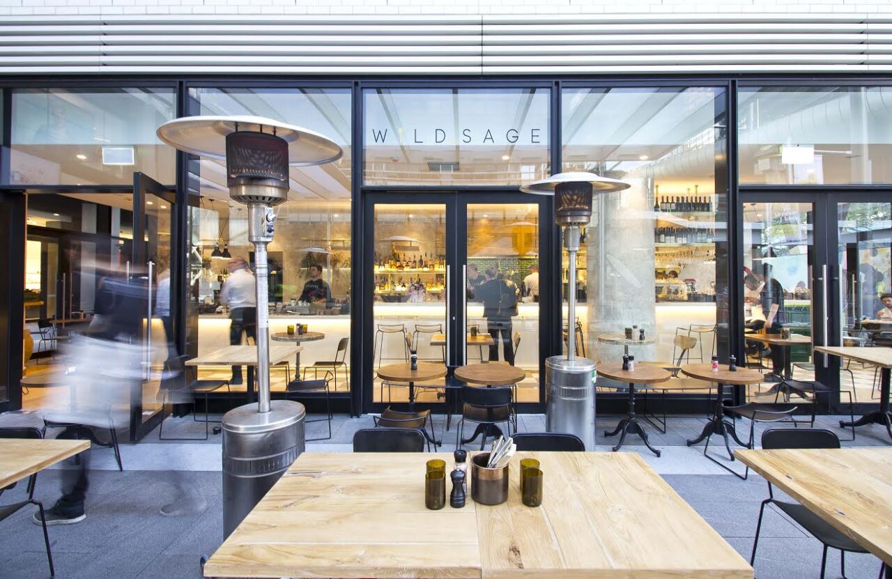Outdoor tables and chairs sit before a restaurant