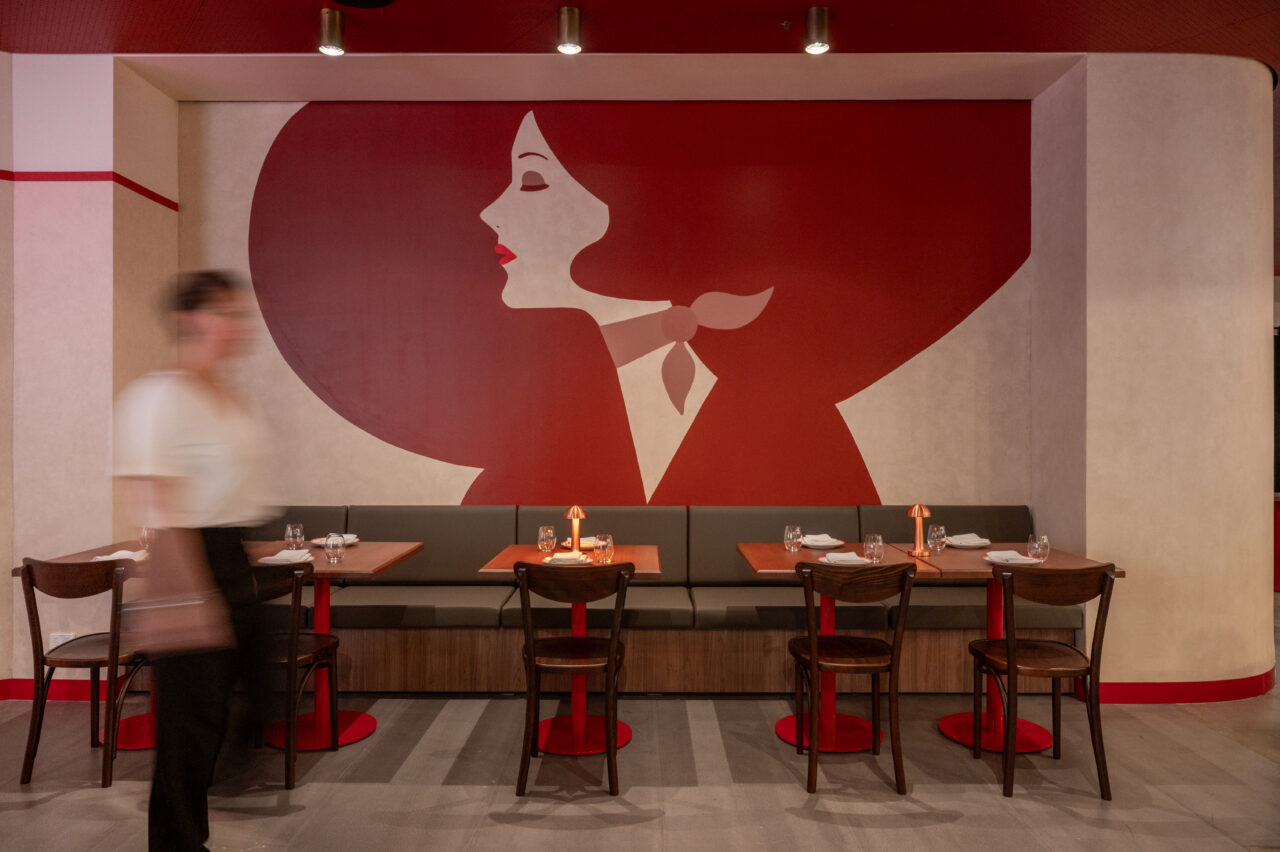A large mural of a woman's profile, in red tones, is displayed on a restaurant wall