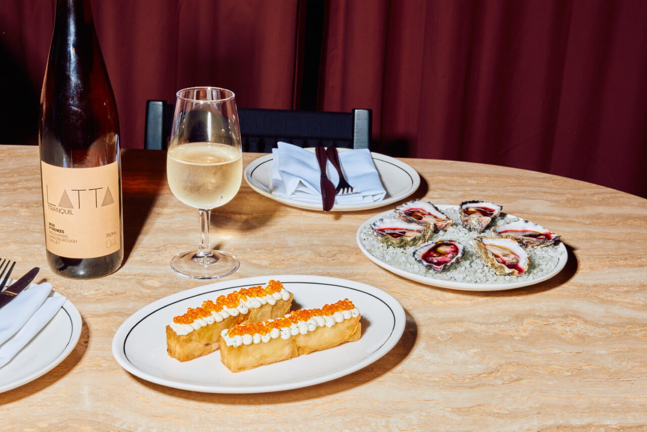 Two fried potato slices topped with a creamy spread and orange roe are presented on a plate