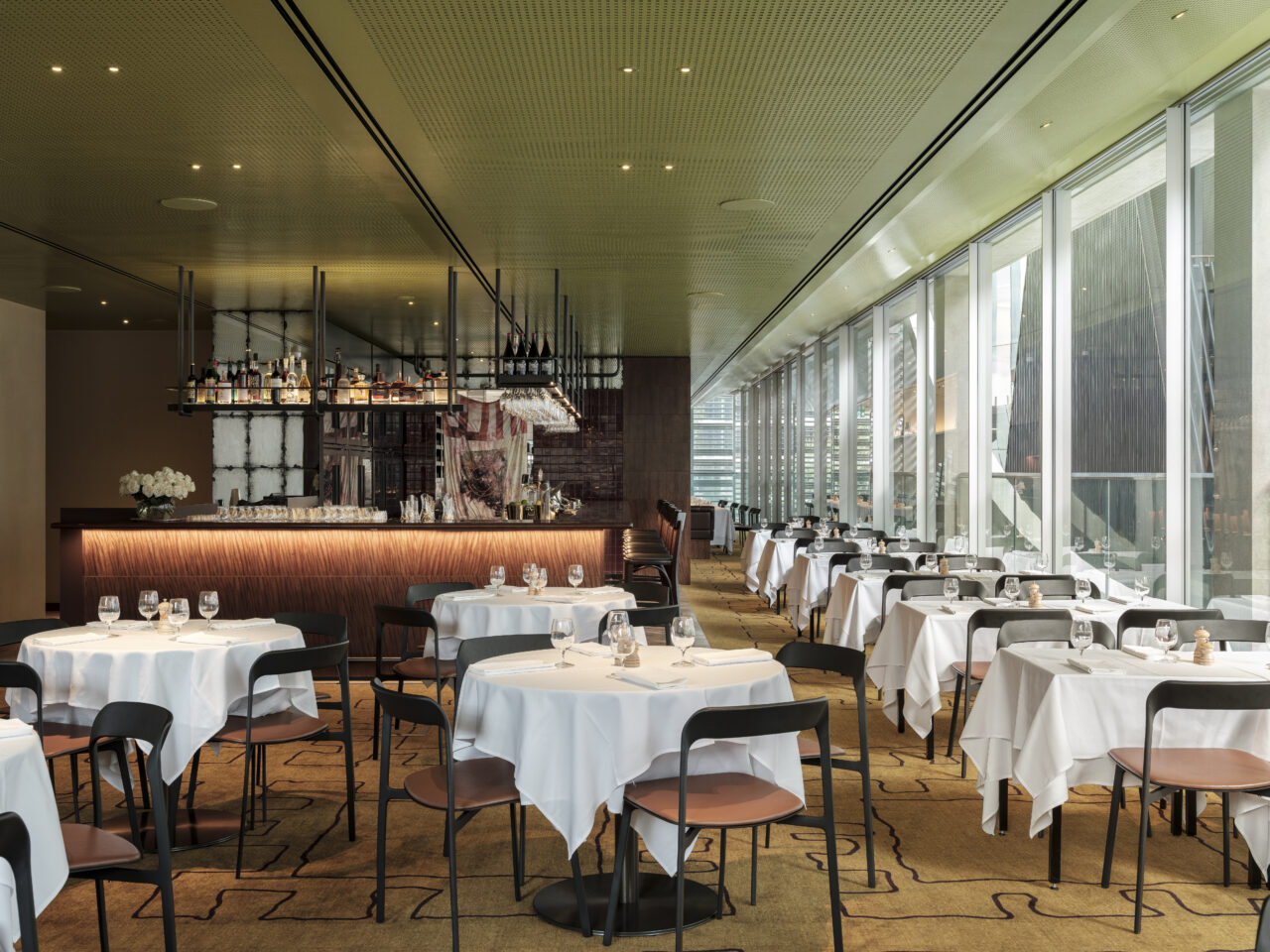 Tables and chairs are arranged in a restaurant; they are set for diners