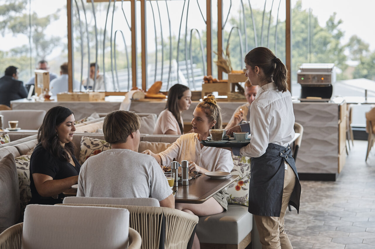 A waitress carries coffee drinks to a table of diners