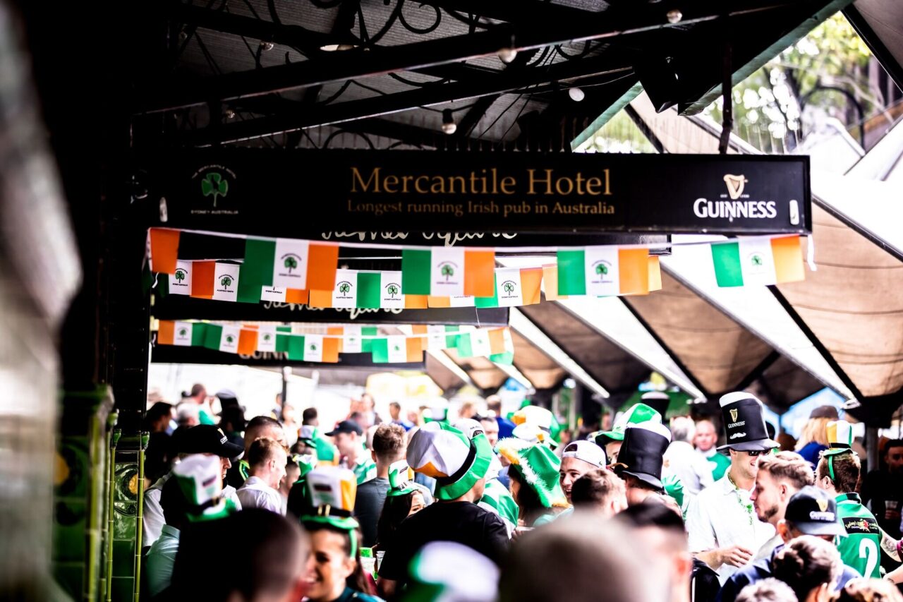 A crowd of people, many wearing Irish-themed hats, gather outside the Mercantile Hotel, the longest-running Irish pub in Australia