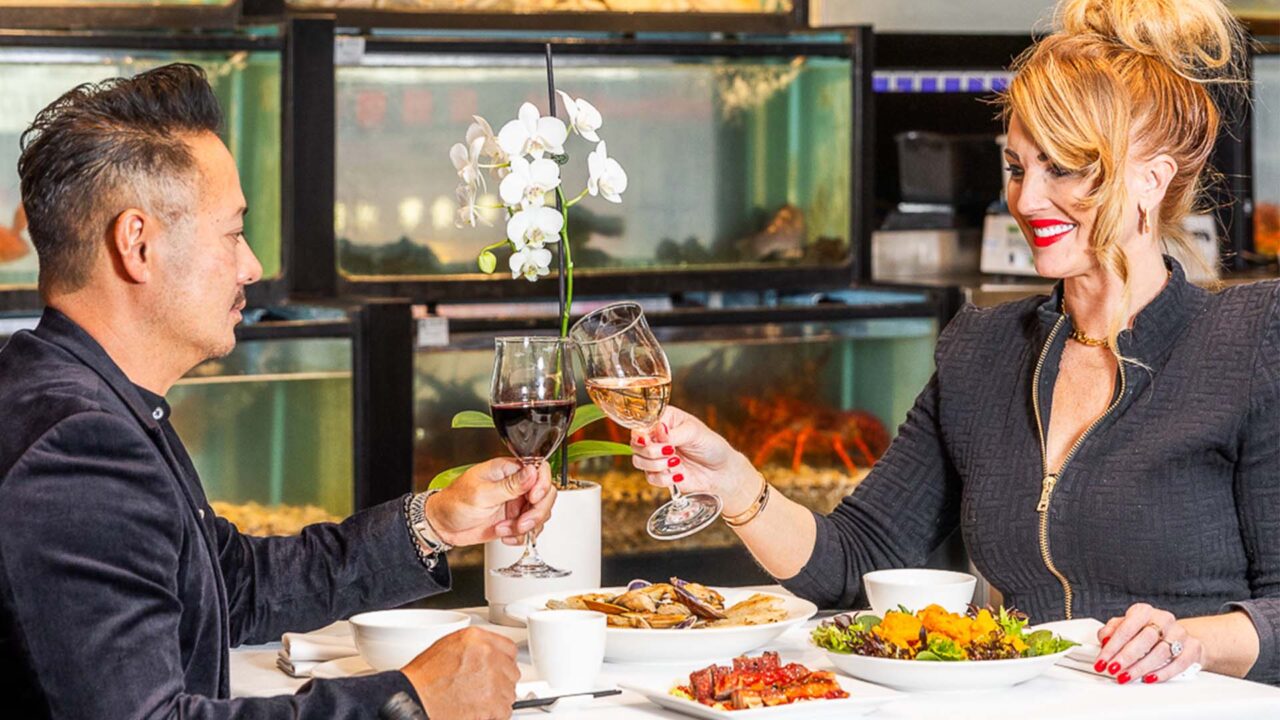 Two people toast with wine glasses at a restaurant