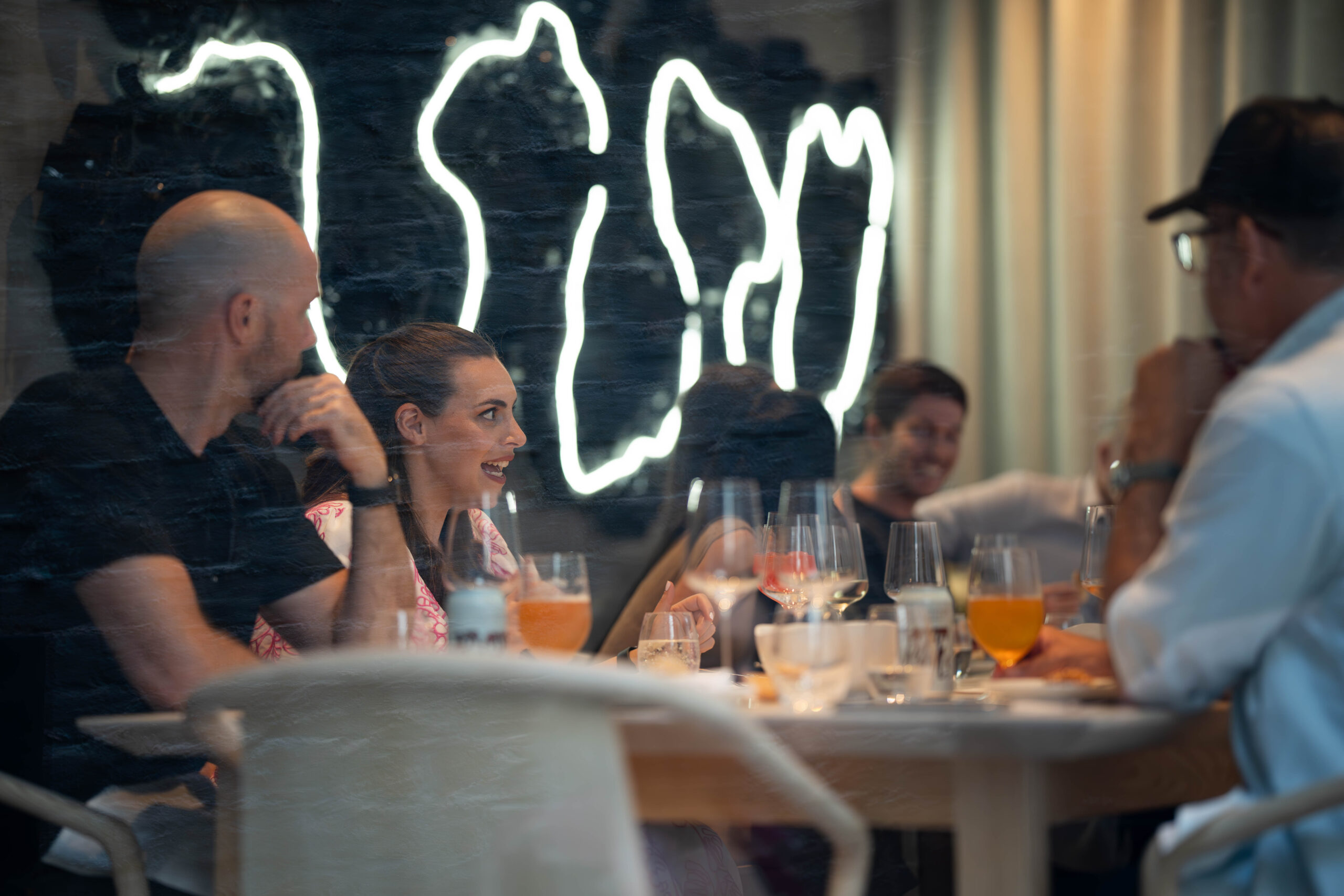 A woman is smiling and conversing with others at a restaurant table