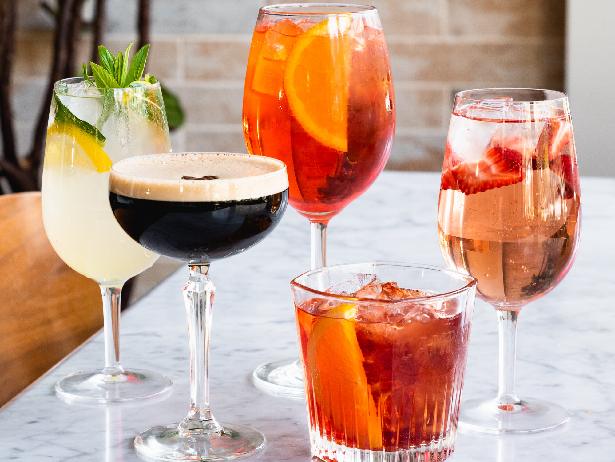 Five mixed drinks sit on a marble table