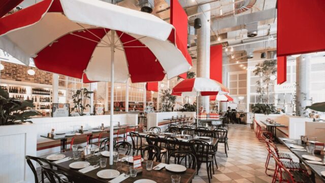 Red and white umbrellas shade tables and chairs in a restaurant