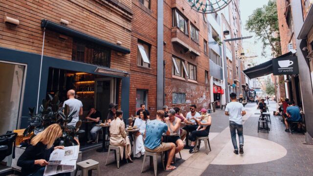 Patrons sit at tables outside a cafe, enjoying food and drinks