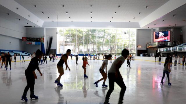People ice skate in a large indoor rink