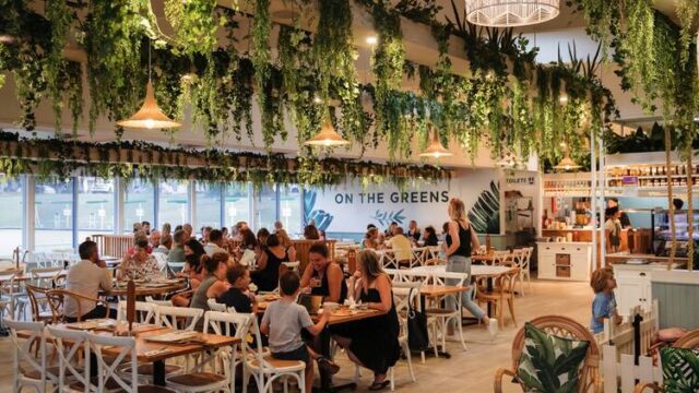 A restaurant, "ON THE GREENS," is filled with people dining