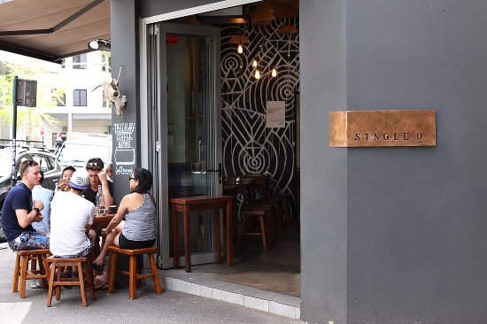 People sit at small tables outside a café, enjoying drinks