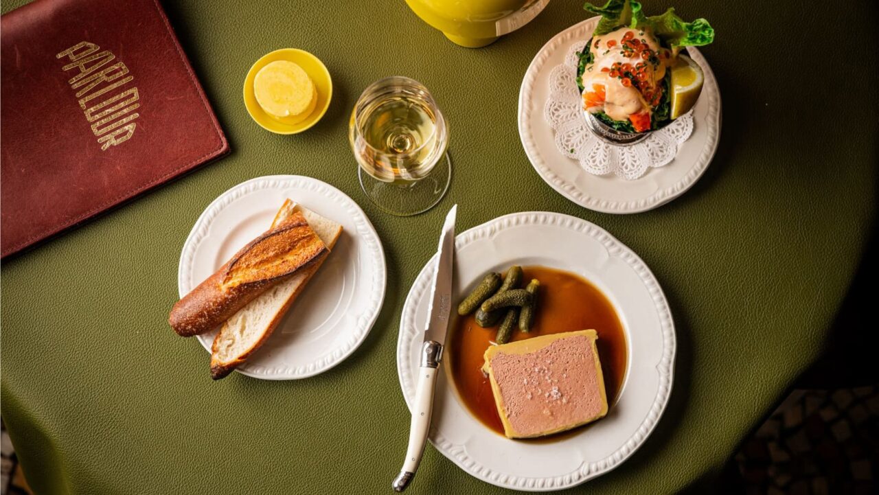 A pâté, served with gherkins and sauce, sits on a plate