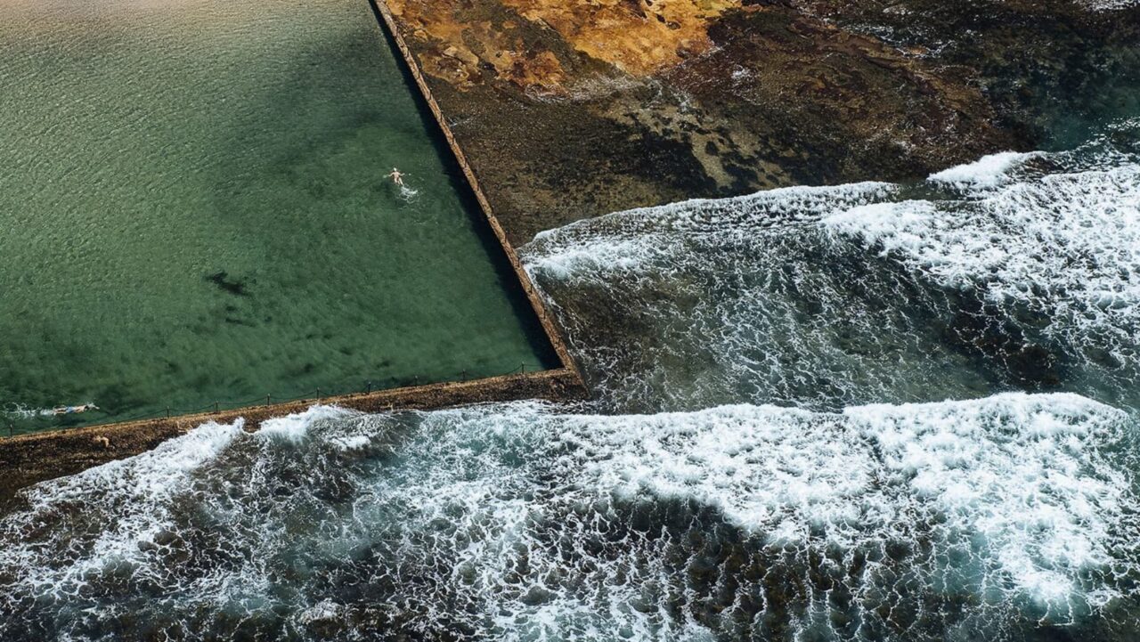 A rock pool is situated next to crashing ocean waves