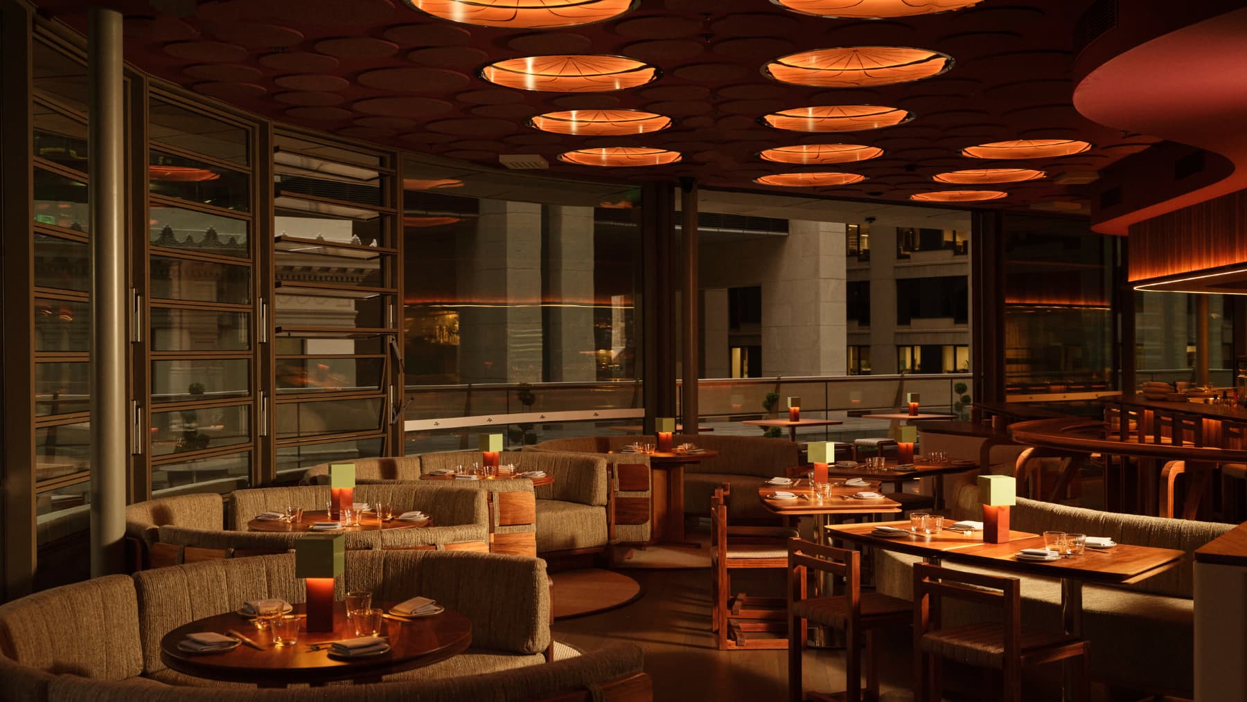 A restaurant's booths and tables are arranged within a modern space, illuminated by warm ceiling lights