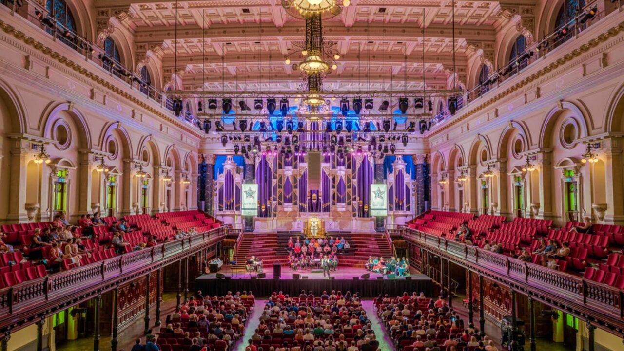 A large audience attends a performance in a grand hall