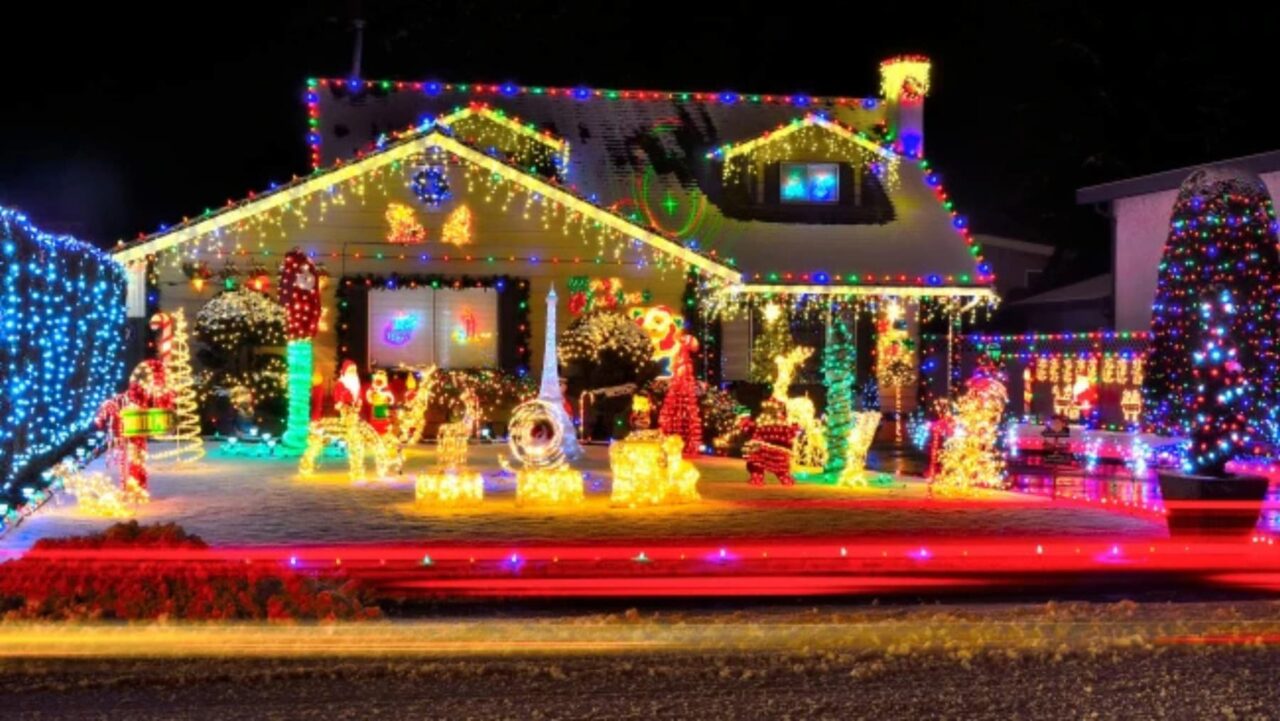 A house is adorned with numerous colorful Christmas lights outlining its shape and forming various festive figures in the yard at night