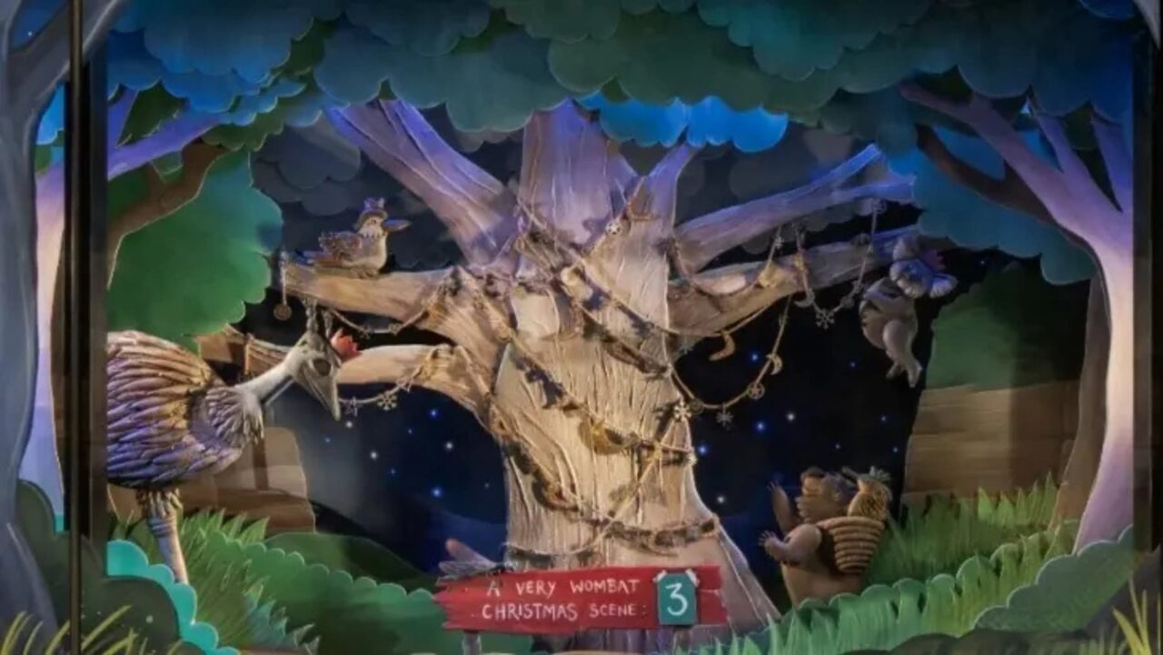 A diorama depicts an Australian Christmas scene at night, featuring various native animals adorning a large tree with ornaments