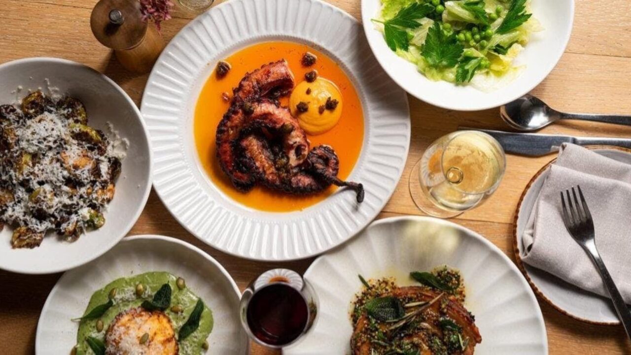 Grilled octopus rests on an orange sauce; Brussels sprouts, a salad