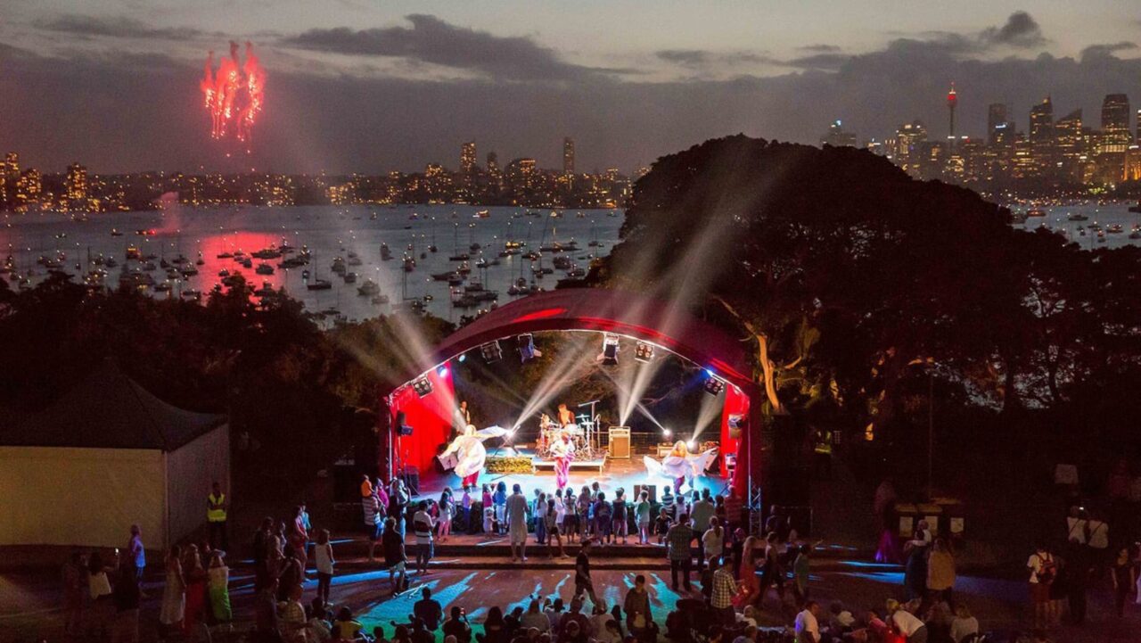 A stage with performers is being illuminated by spotlights