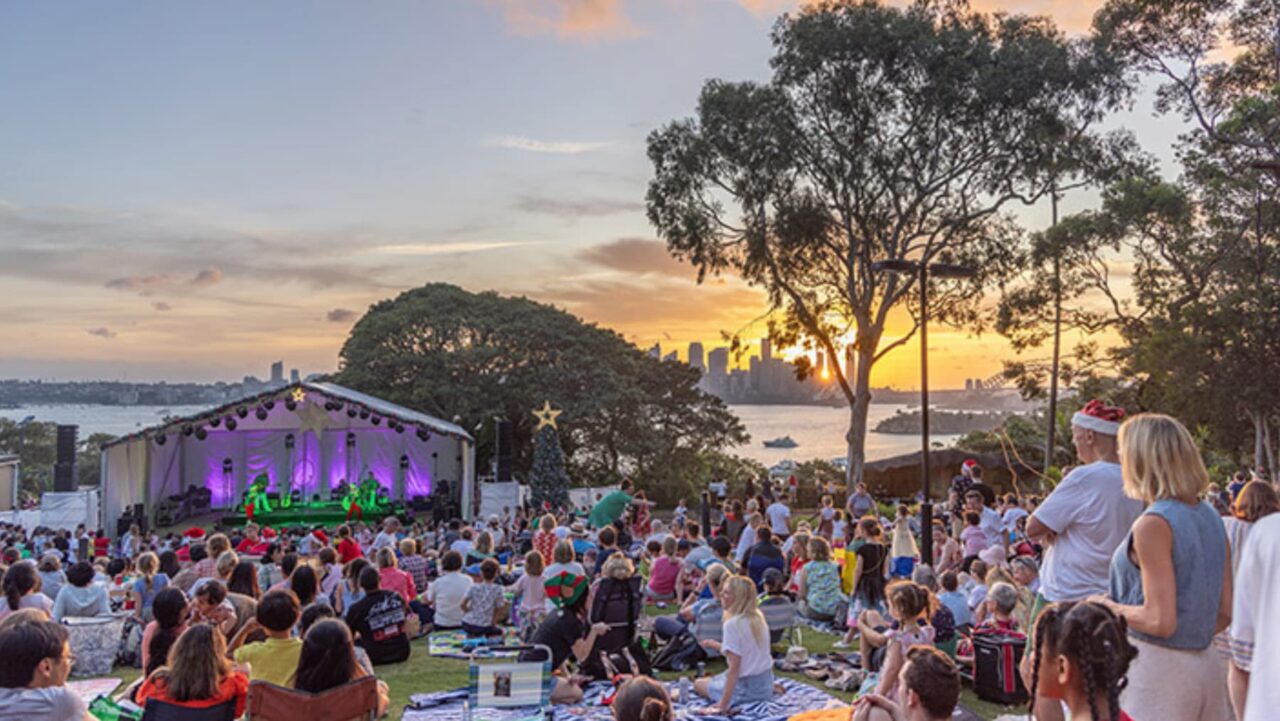 Crowds of locals watching the Christmas concert at Taronga Zoo with a view of Sydney Harbour in the background.