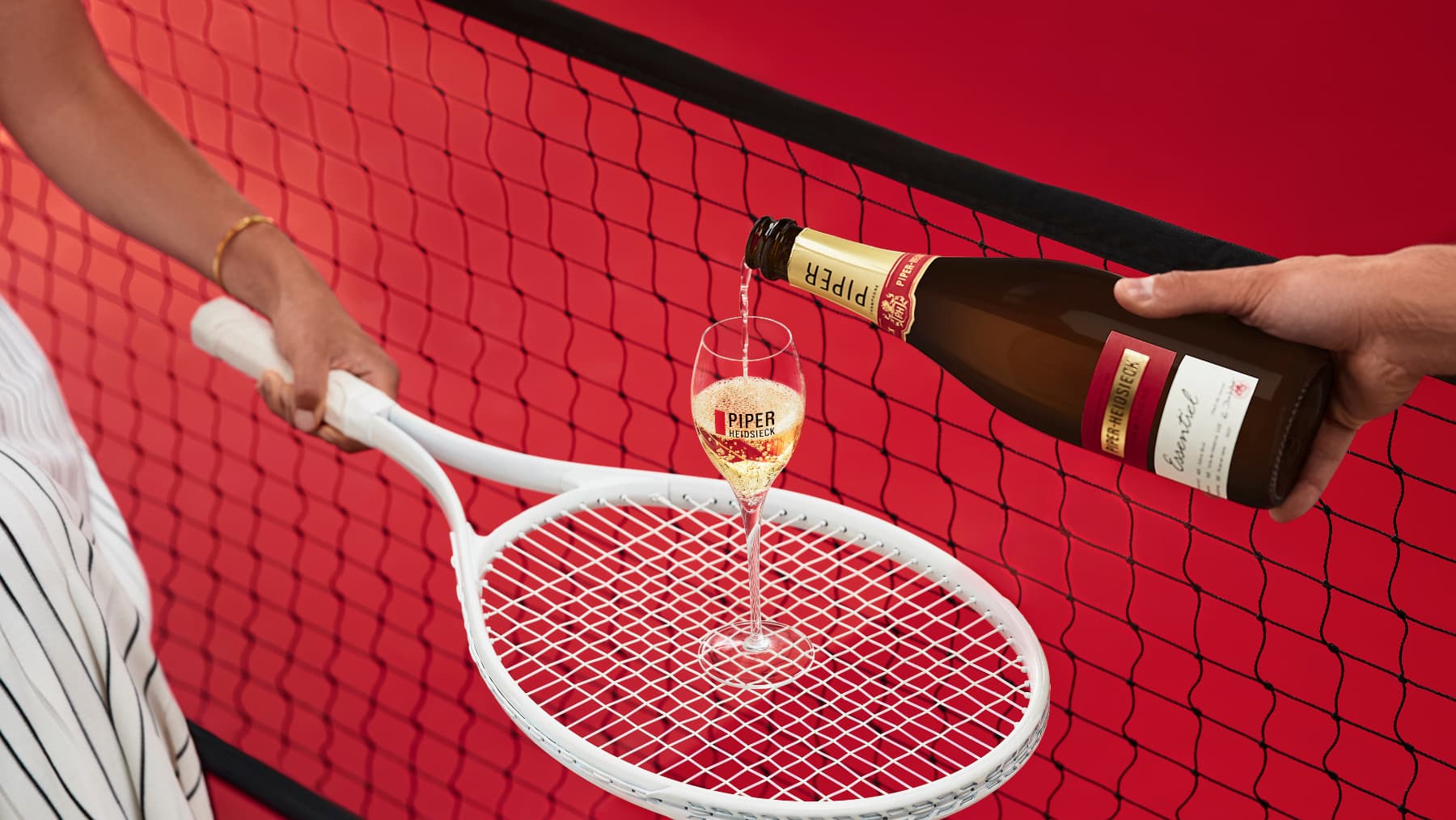 A bottle of Champagne being poured into a glass that sits on a tennis racket