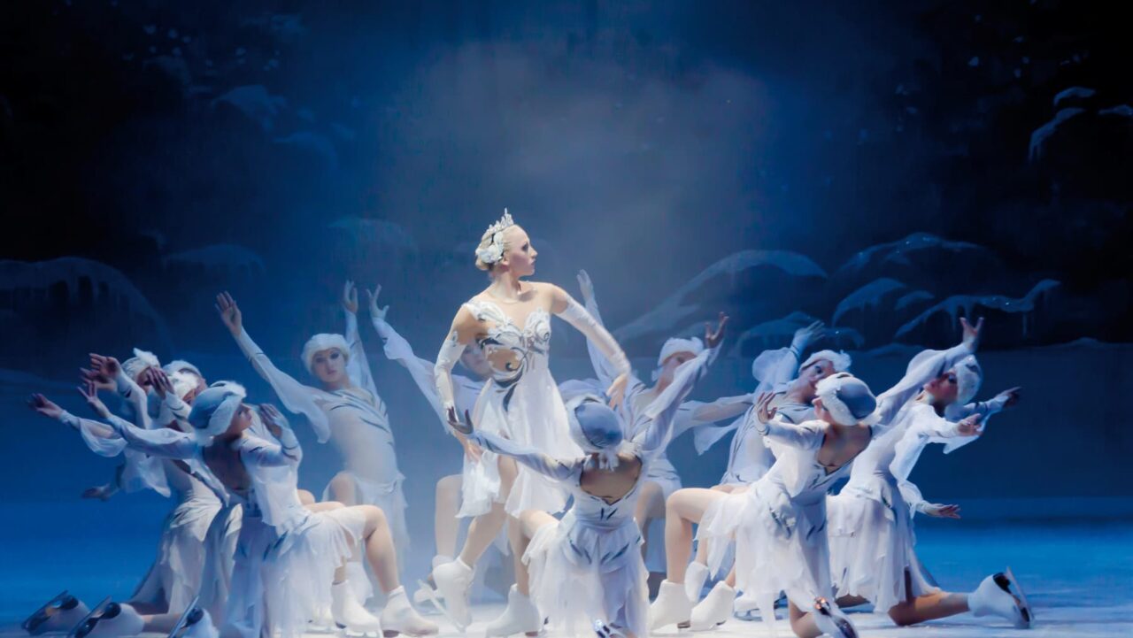 a group of women in white dresses dancing on a stage