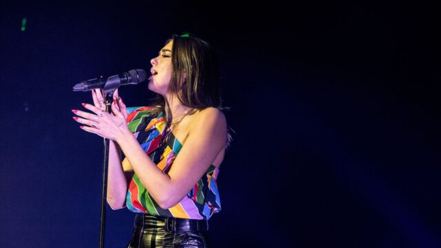 Fans prepare to see Dua Lipa in Sydney. She is pictured on stage against a dark background