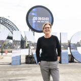 Vivid Sydney is looking for a new Festival Director. Pictured is Gill Minervini, the current Festival Director, in front of a large Vivid Sydney sign.