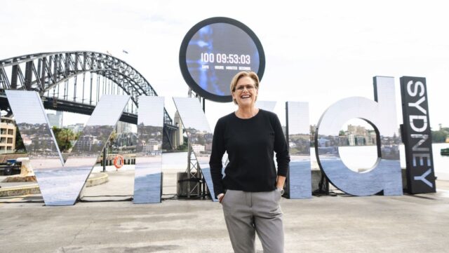 Vivid Sydney is looking for a new Festival Director. Pictured is Gill Minervini, the current Festival Director, in front of a large Vivid Sydney sign.