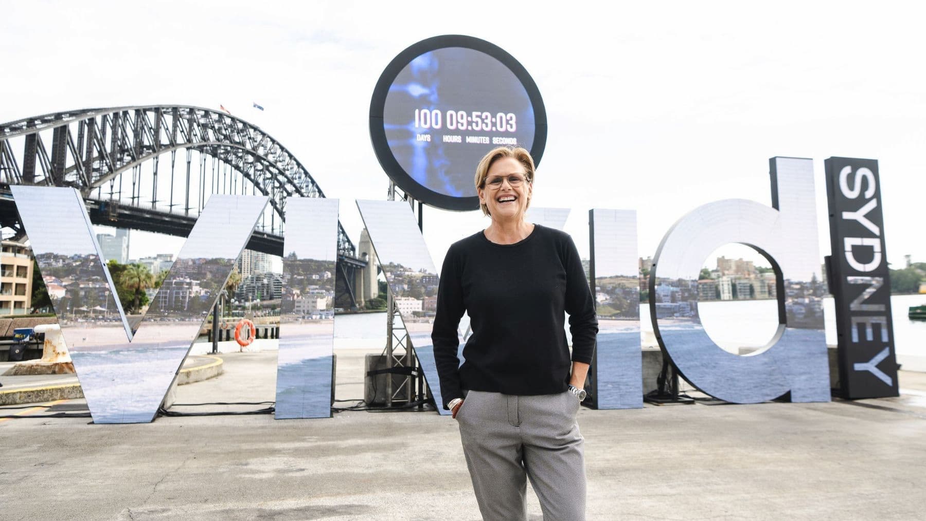 Vivid Sydney is looking for a new Festival Director. Pictured is Gill Minervini, the current Festival Director, in front of a large Vivid Sydney sign.