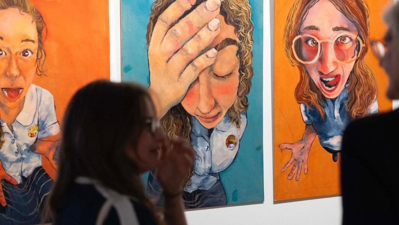a girl stands in front of her artwork at ARTEXPRESS