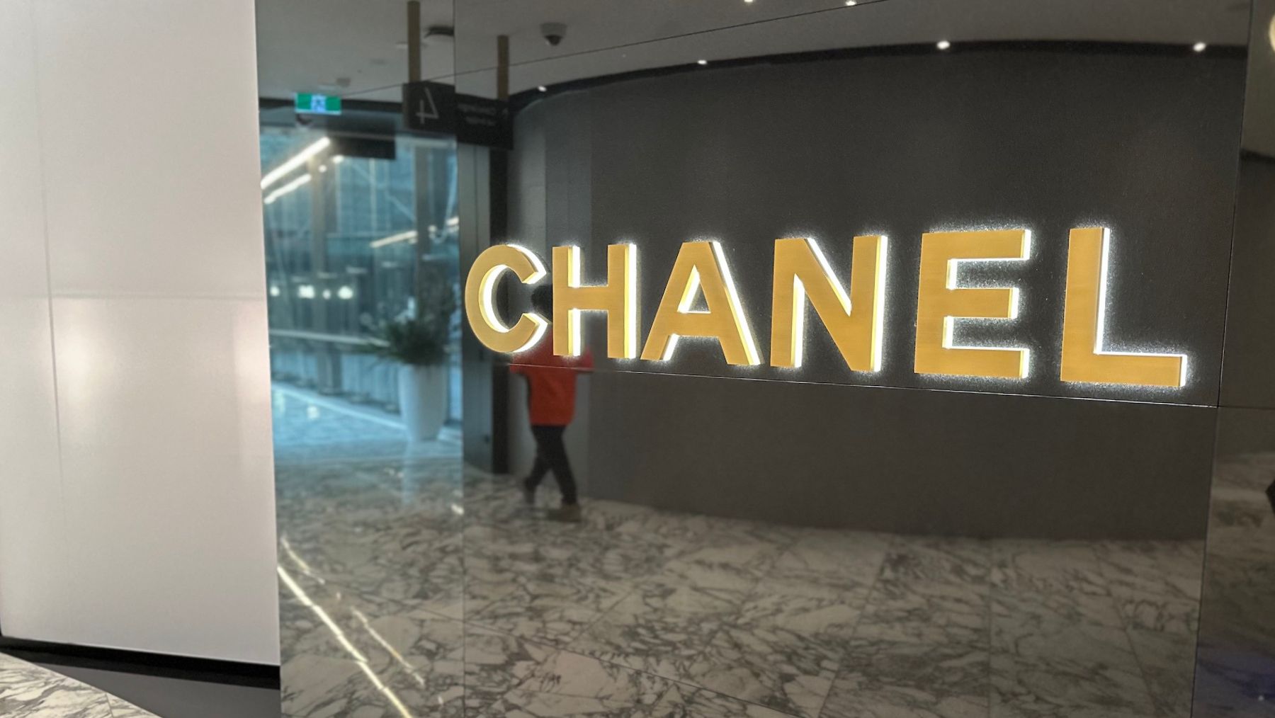 a person standing in a hallway with a glass wall with a sign