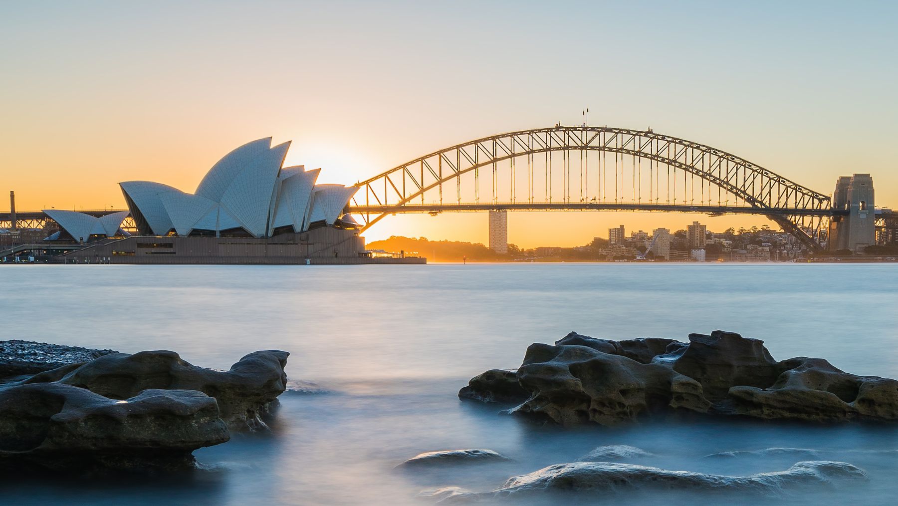 a bridge over water with a building and a city in the background