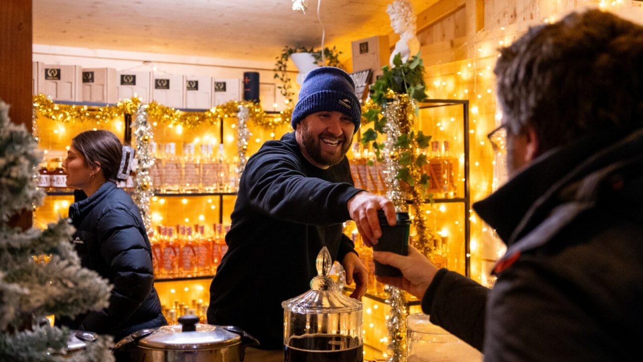 a man in a beanie handing a cup to another man