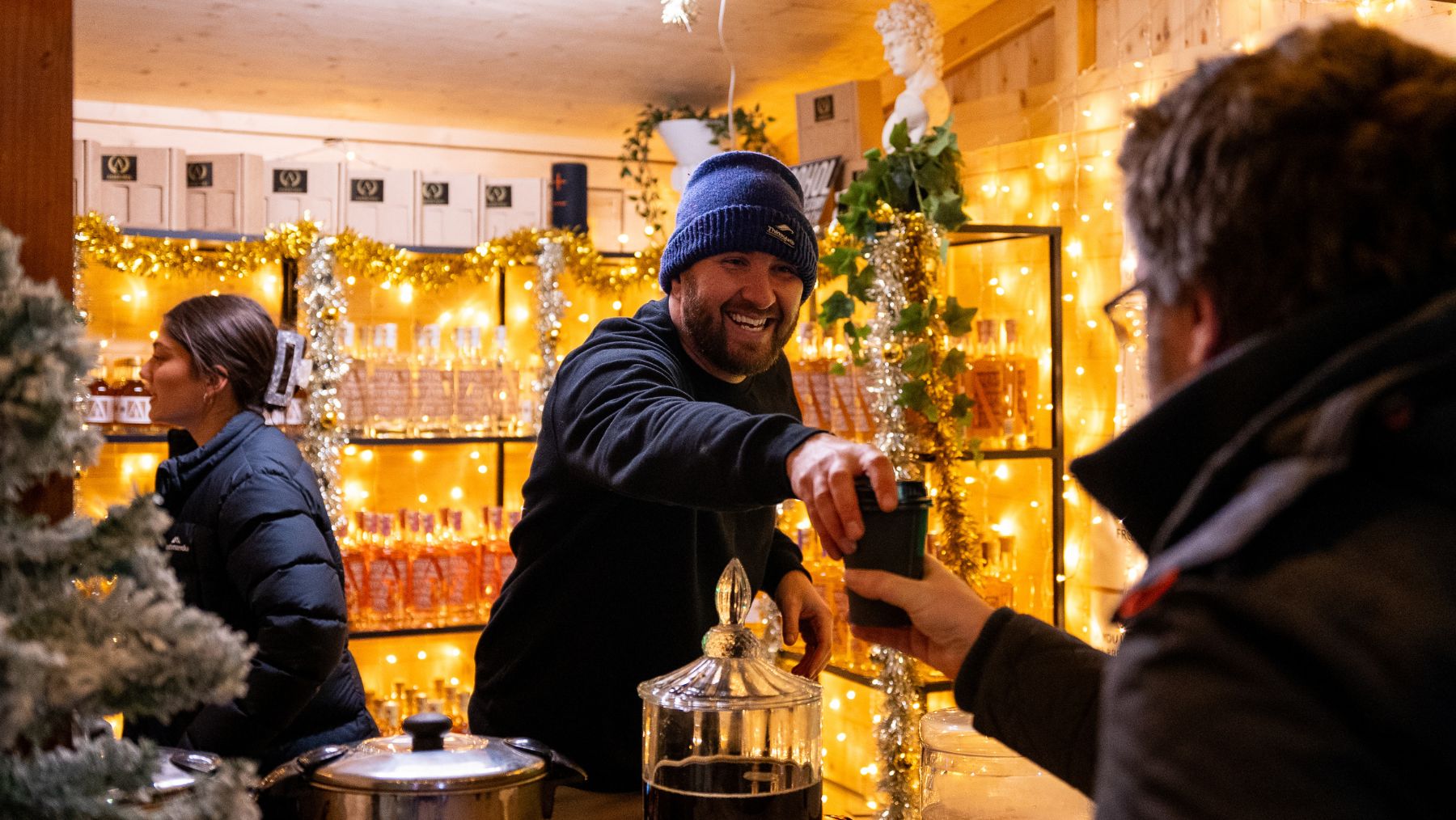 a man in a beanie handing a cup to another man