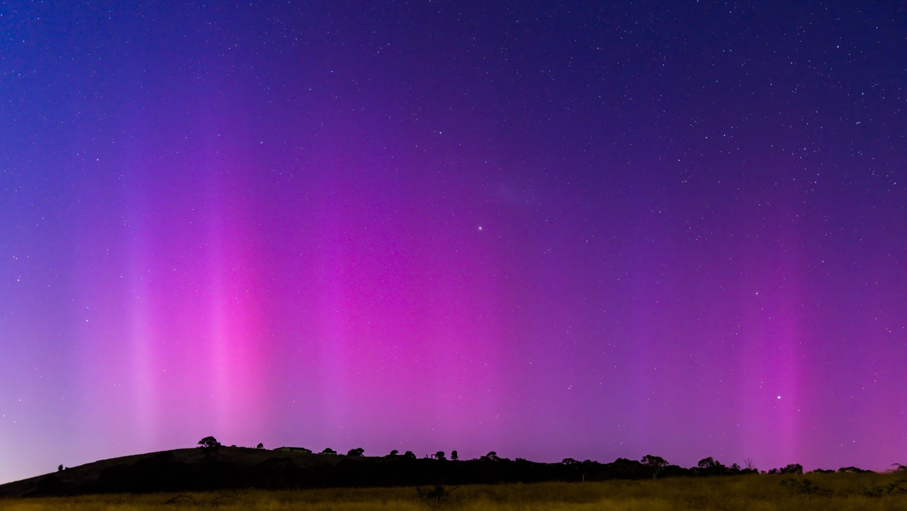 The Southern Lights - Aurora Australis and the predawn night sky filled with pink streaks in Blayney, Central West, NSW, Australia.
