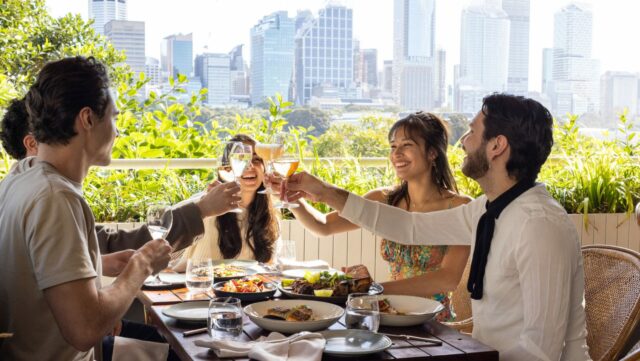 a group of people sitting at a table with food and drinks