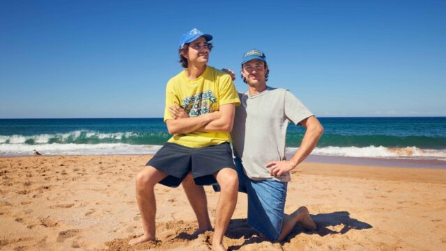 two men posing for a picture on a beach