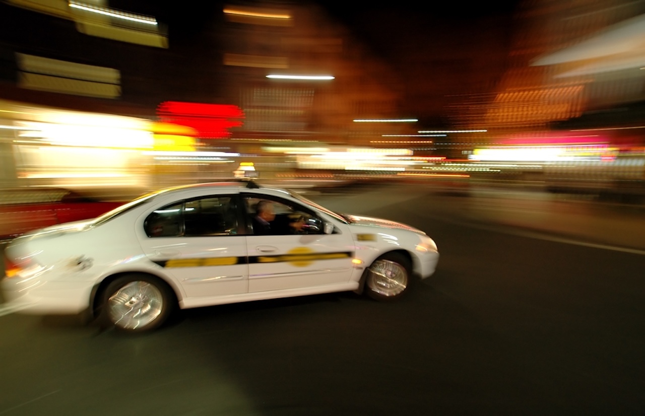 a white taxi driving down the street