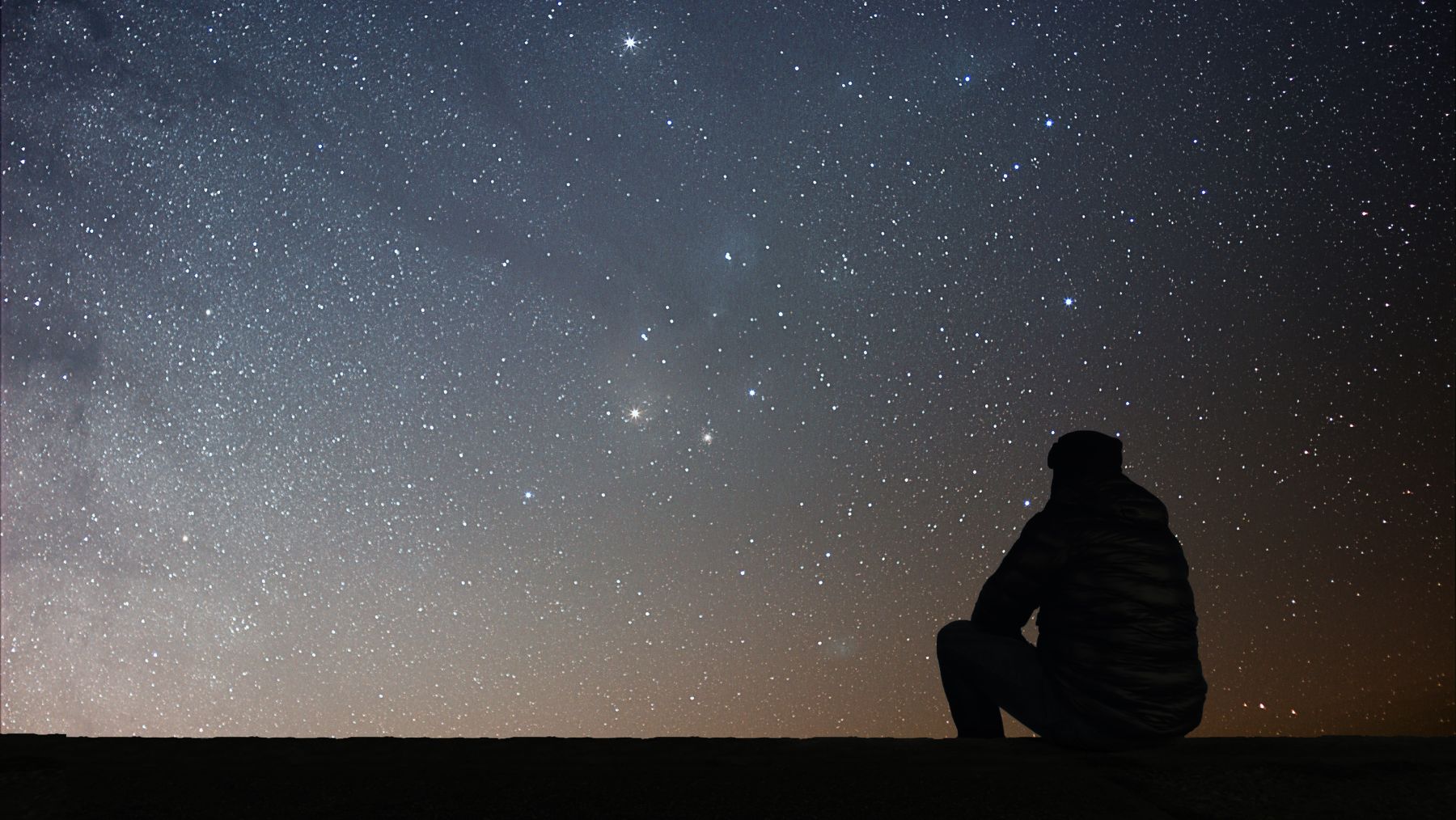 silhouette of a man watching a meteor shower