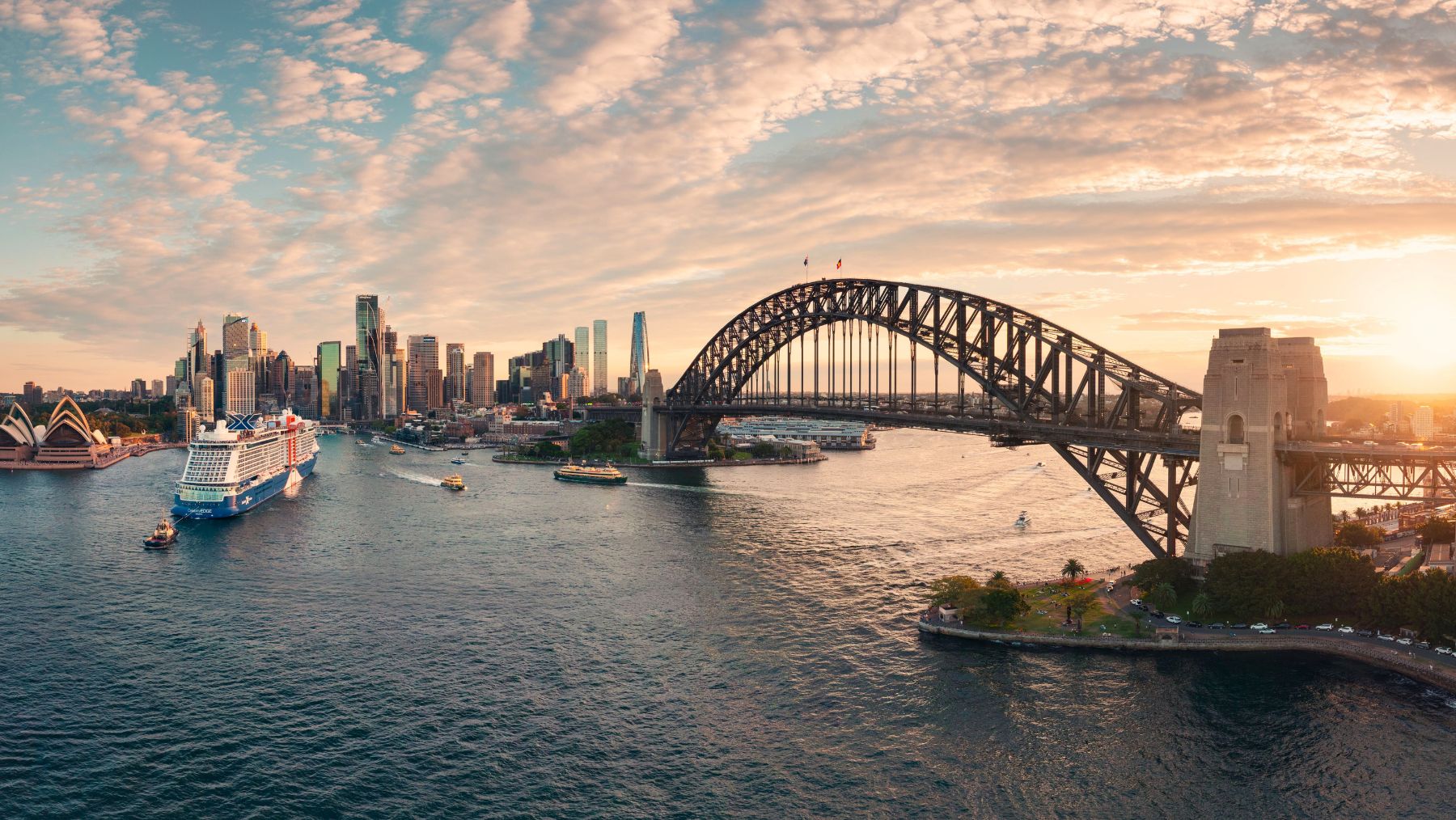 Sydney Harbour Bridge and Sydney Opera House during sunset, with a cruise ship leaving the harbour