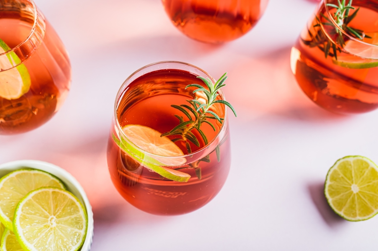 Delicious Negroni cocktail with lime and rosemary in glasses