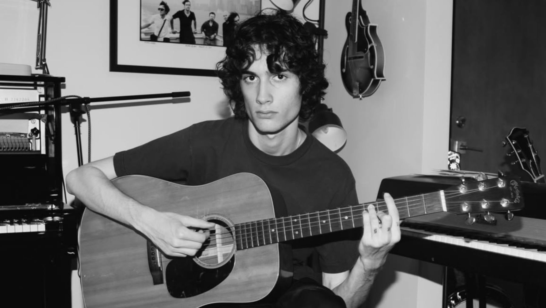 the artist SOMBR sat holding a guitar