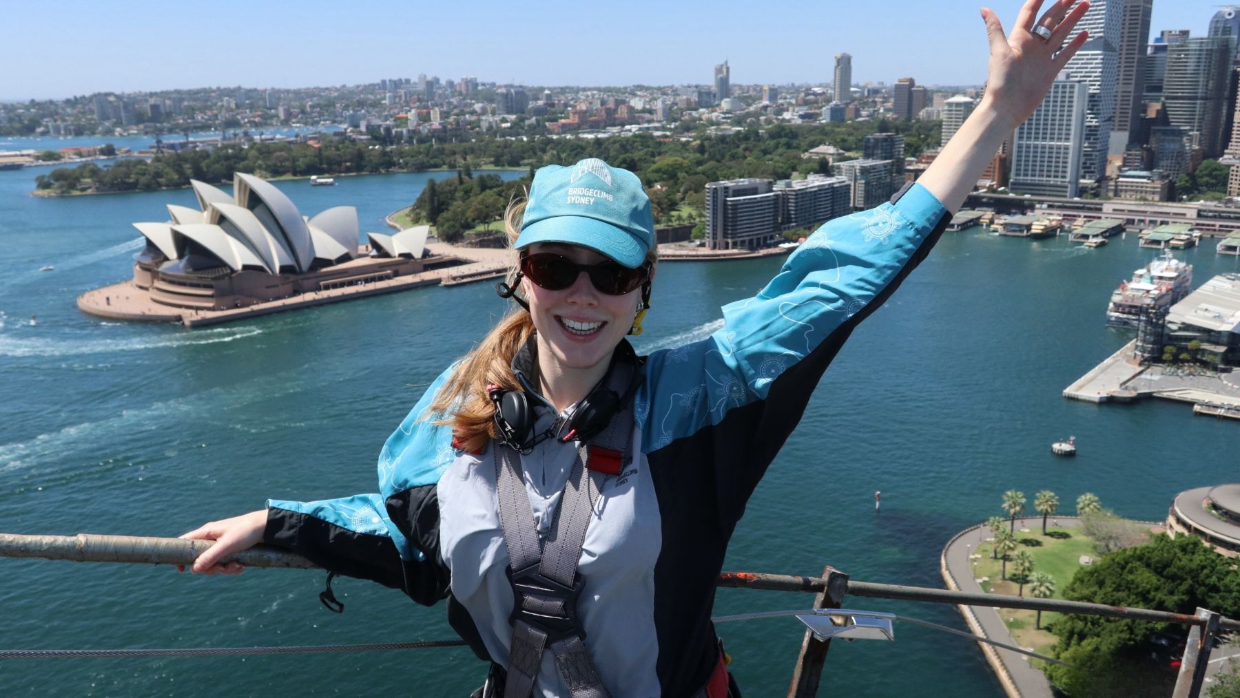 a climber smiles on top of the Sydney Harbour Bridge