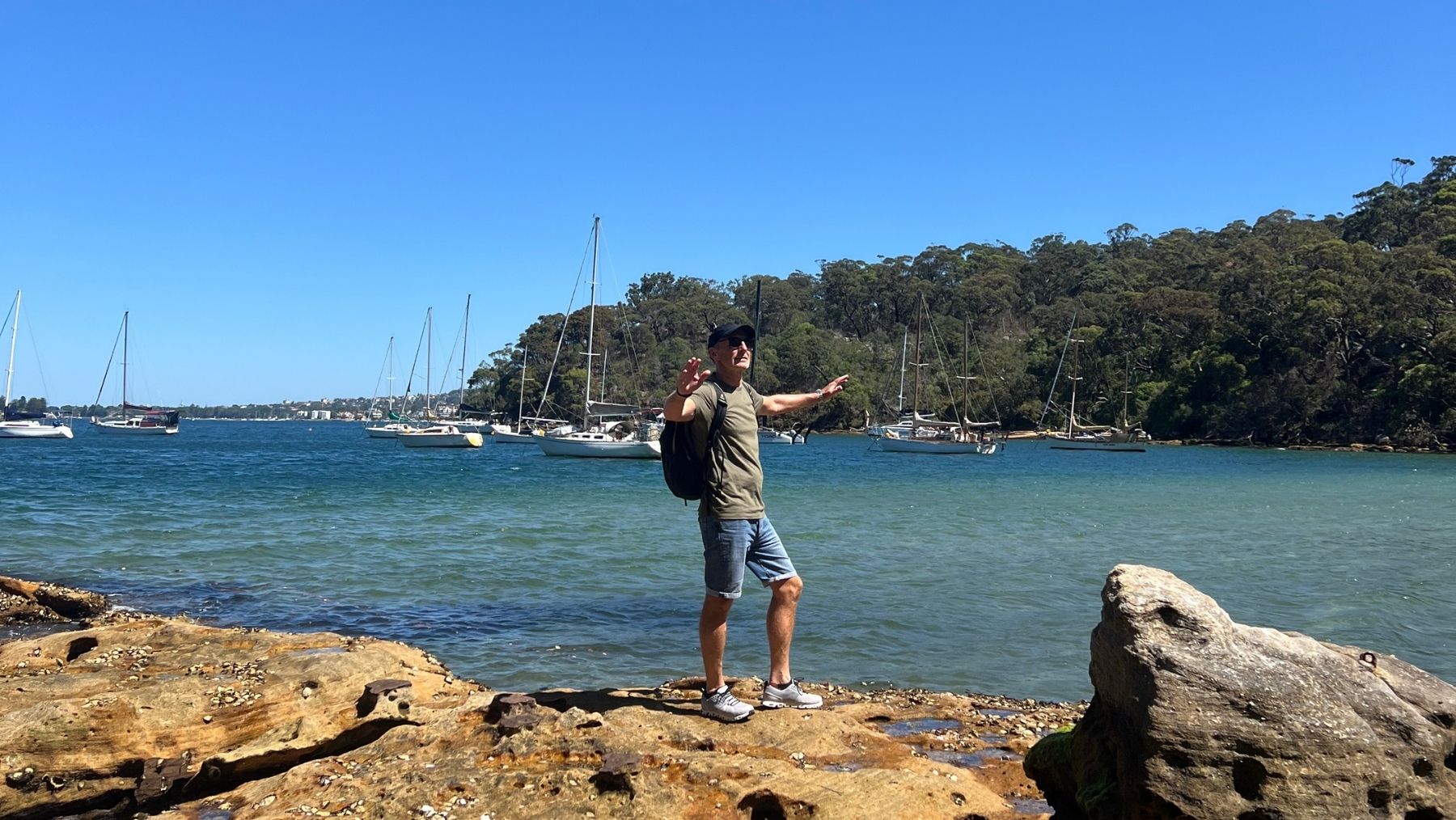 a man stands on rocks near Taylors Bay Beach