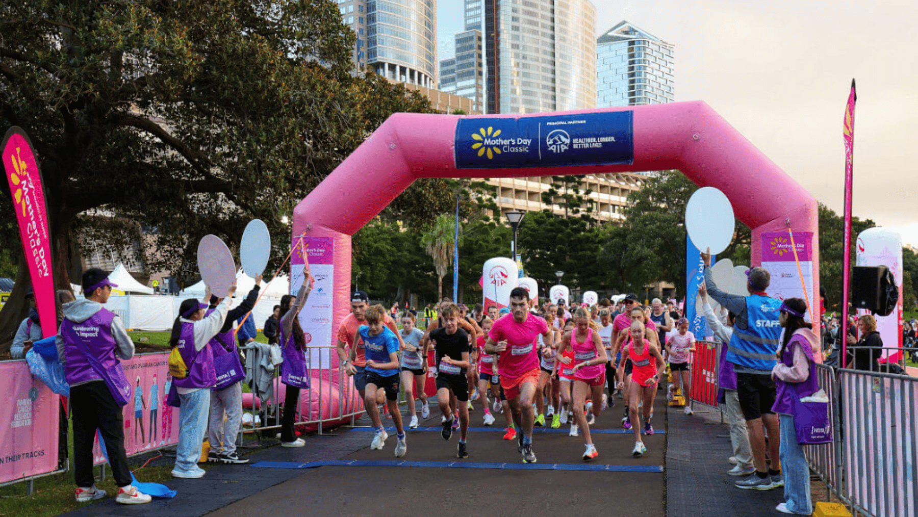 A large group of runners in pink set off on a fun run