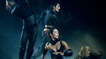 four dancers in black on a smoky stage
