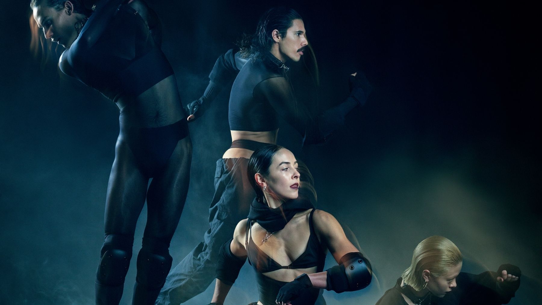 four dancers in black on a smoky stage