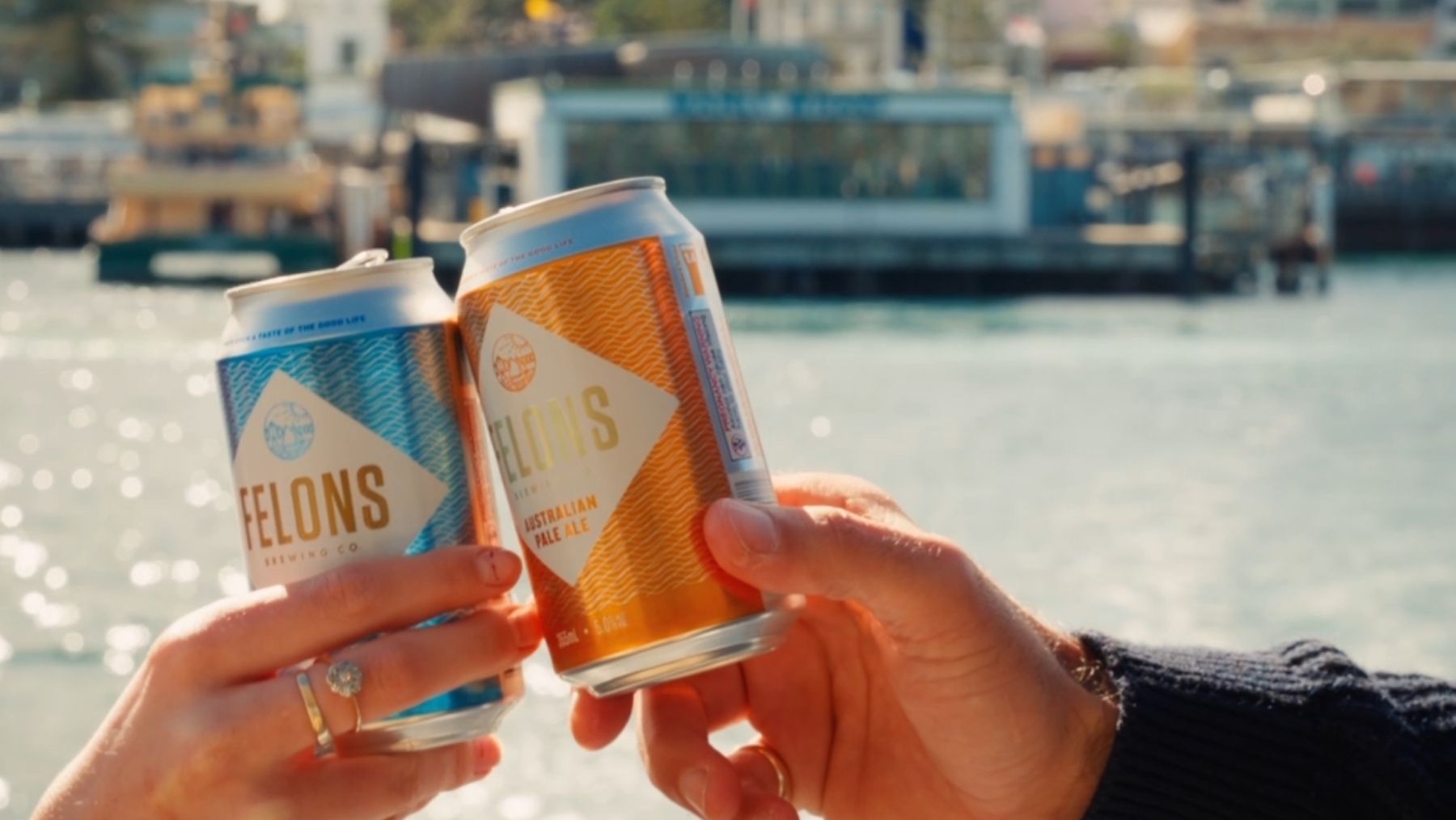 Two cans of beer with a wharf in the background